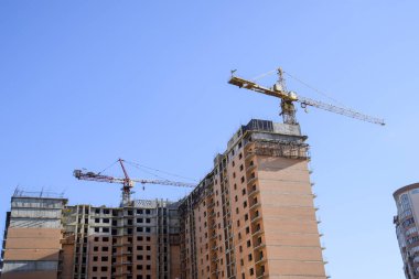 Yeni bir ev inşası. Kule Vinç mavi gökyüzü ve güneş karşı bina. Bir vinç ile yeni binaların inşası. Kule Vinç.