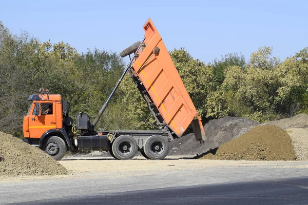 La camioneta descarga escombros. El camión tiró la carga. Arena y grava. Construcción de carreteras —  Fotos de Stock