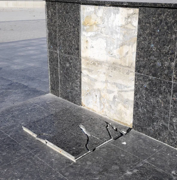 The ruined marble tile that fell off from the base of the monument.