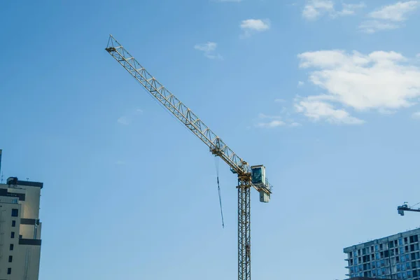 Tower building crane against the blue sky and sun. Construction of new buildings with a crane. Tower crane.