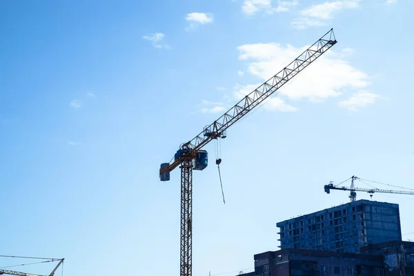 Tower building crane against the blue sky and sun. Construction of new buildings with a crane. Tower crane.