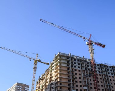 Kule Vinç mavi gökyüzü ve güneş karşı bina. Yeni bir ev inşası. Bir vinç ile yeni binaların inşası. Kule Vinç