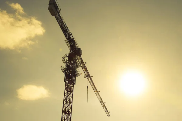 Torre de construcción de grúa contra el cielo azul y el sol. Construcción de una casa nueva. Construcción de nuevos edificios con grúa. Grúa torre — Foto de Stock