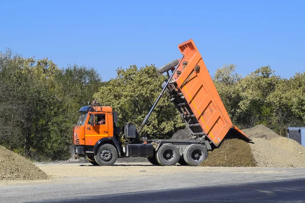 O camião descarrega escombros. O camião largou a carga. Areia e cascalho. Construção de estradas — Fotografia de Stock