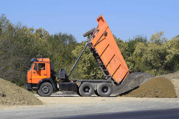 The dump truck unloads rubble. The truck dumped the cargo. Sand and gravel. Construction of roads.