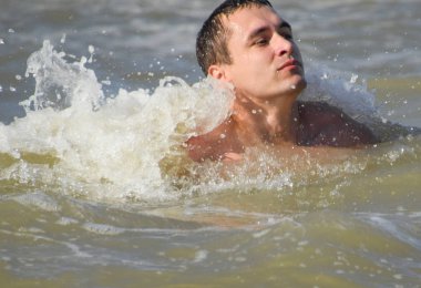 Deniz suyu atletik bir adam. Denizde yüzme. Bir adam denizin dalgaları arasında Yüzme.