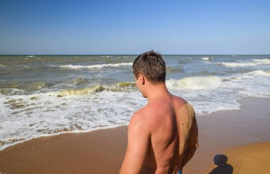 Atletik adam sahilde. Bir erkek deniz suya gider.