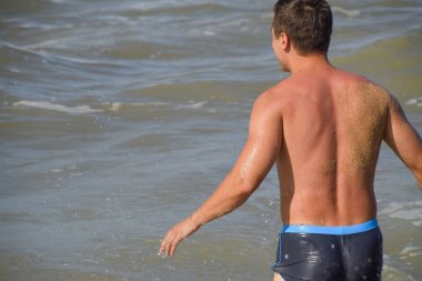 Atletik adam sahilde. Bir erkek deniz suya gider.