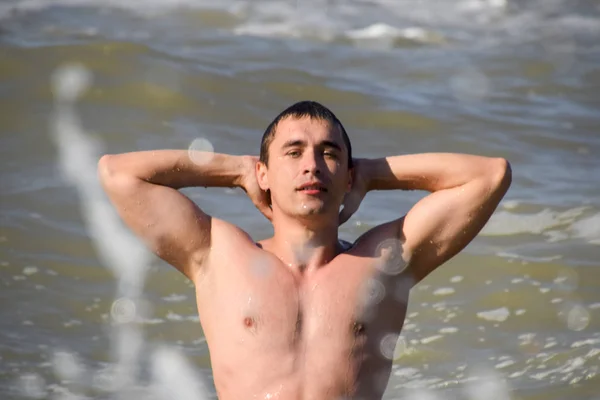 Athletic man in sea water. Bathing in the sea. A man is swimming among the waves of the sea.
