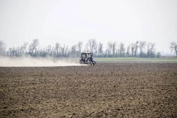 Το τρακτέρ Βολοκόποι το χώμα στο χωράφι και δημιουργεί ένα σύννεφο σκόνης πίσω από το — Φωτογραφία Αρχείου