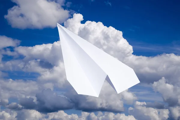 White paper airplane in a blue sky with clouds. The message symbol in the messenger