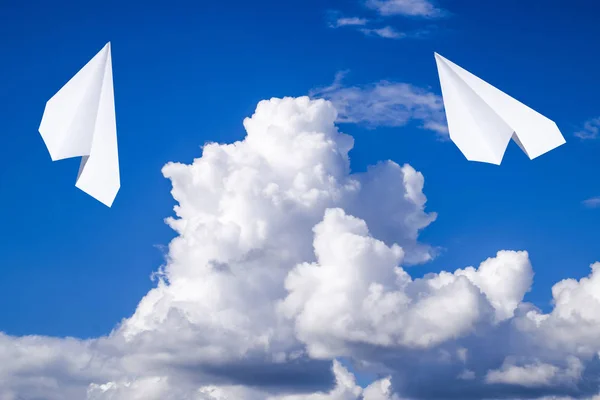 White paper airplane in a blue sky with clouds. The message symbol in the messenger