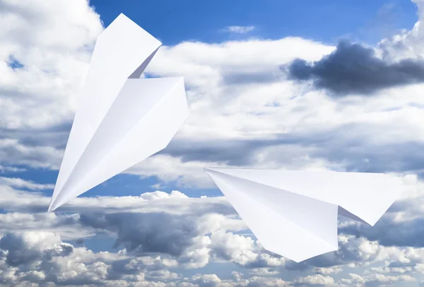 White paper airplane in a blue sky with clouds. The message symbol in the messenger