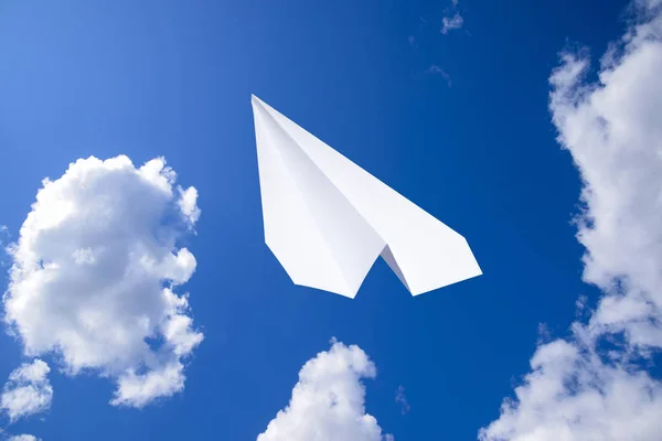 White paper airplane in a blue sky with clouds. The message symbol in the messenger