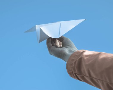 Gökyüzüne karşı elinde beyaz kağıt uçak. İnternette özgürlüğün sembolü