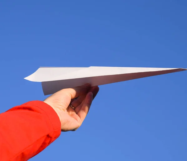 Fehér papír repülőgép a kezét az ég ellen. Az interneten a szabadság jelképe. — Stock Fotó