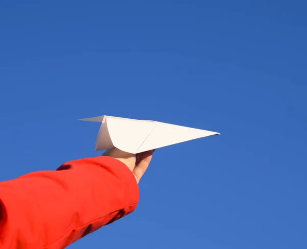 White paper airplane in hand against the sky. A symbol of freedom on the Internet.