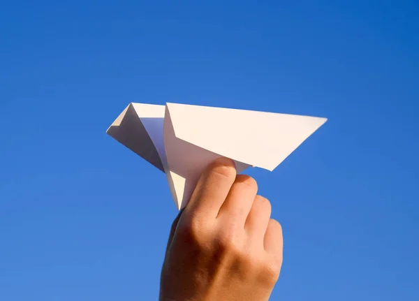 White paper airplane in hand against the sky. A symbol of freedom on the Internet.