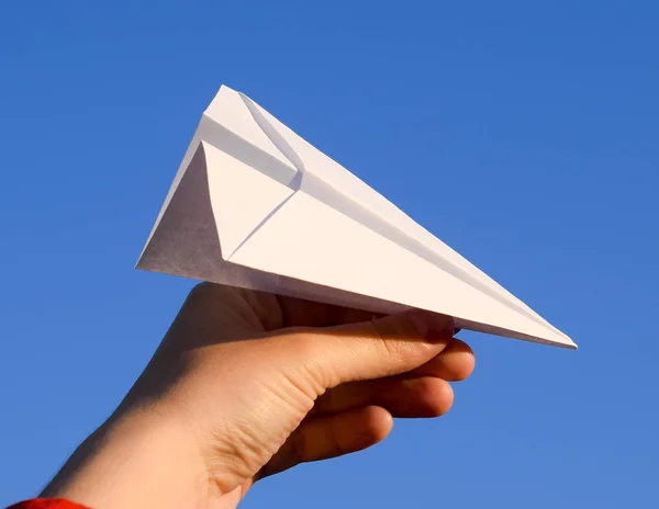 White paper airplane in hand against the sky. A symbol of freedom on the Internet