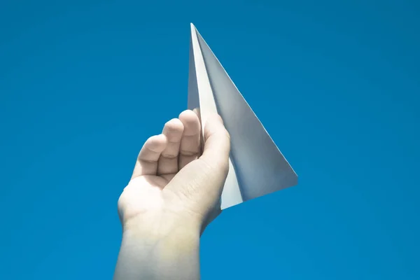 White paper airplane in hand against the sky. A symbol of freedom on the Internet.