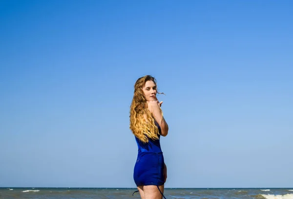 Μια ξανθιά κοπέλα σε ένα μπλε μαγιό στην παραλία. Διακοπές στην παραλία. — Φωτογραφία Αρχείου