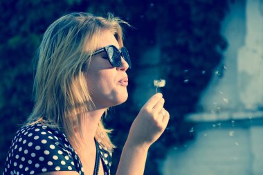 Kız bir karahindiba üzerinde üfleme. Karahindiba tohumları üfleme