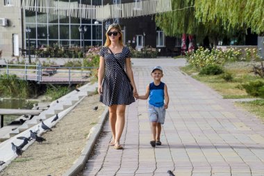 Anne ve oğlu parkta yürüyorlar. Aile yürüyüş