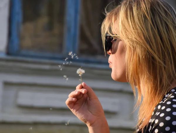 Kız bir karahindiba üzerinde üfleme. Karahindiba tohumları üfleme