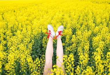 Çiçekler dışarı yapışmasını spor ayakkabı kadın bacaklar. Bacaklar yukarı. Bacaklar sarı tecavüz çiçekleri arka planı