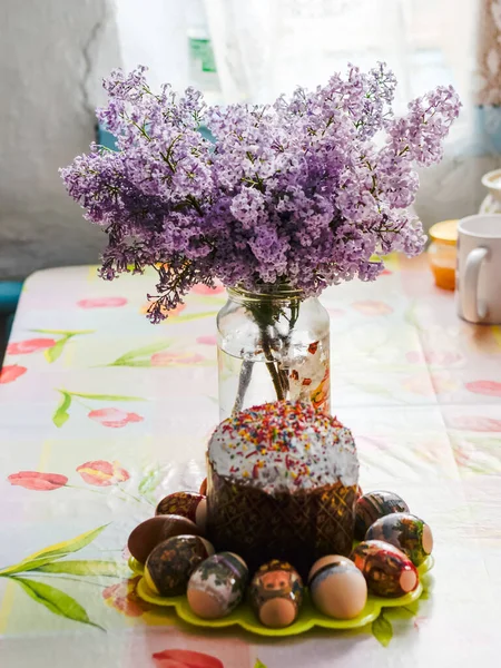Kytice šeříků poblíž velikonoční koláče a obarvená vejce. — Stock fotografie