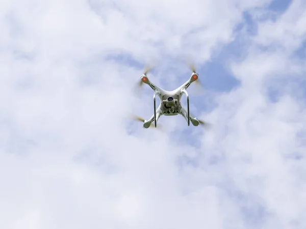 Vuelo quadrocopters blanco contra el cielo azul con nubes —  Fotos de Stock