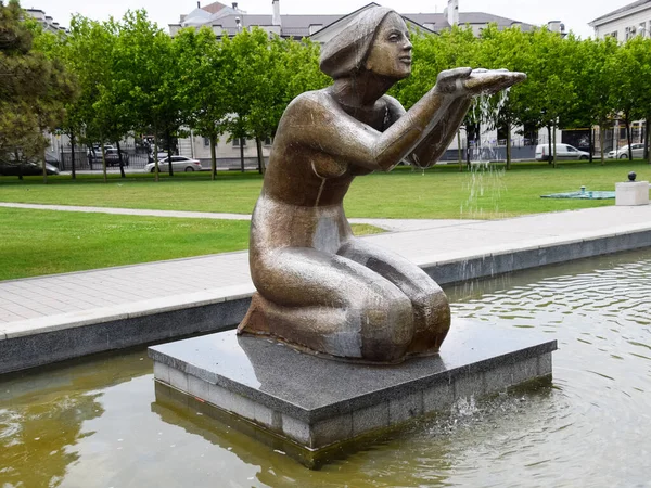 Статуя жінки на колінах у фонтані. Вода тече з — стокове фото