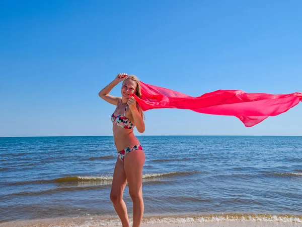Блондинка в бикини, стоящая на пляже и держащая красное с — стоковое фото