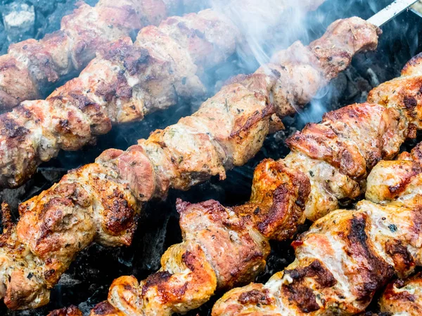 Frying pork on a skewer over a brazier. Turning meat over coals. — Stock Photo, Image