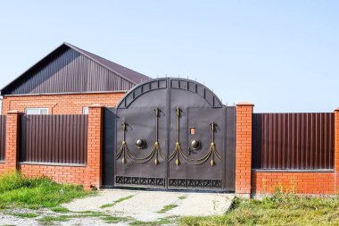 Bir çit ve gates ile tuğla ev. Yeni bir İnşaatlı çit görünümünü