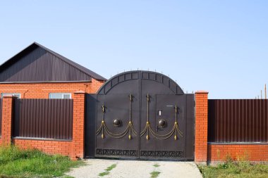 Bir çit ve gates ile tuğla ev. Yeni bir İnşaatlı çit görünümünü