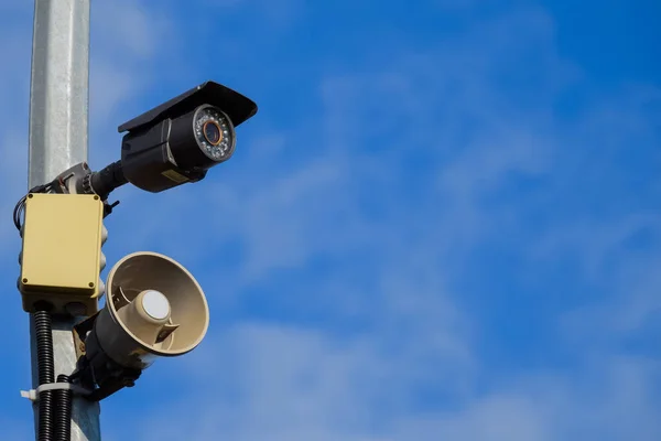 CCTV camera en luidspreker alarm op een paal tegen een blauwe hemel. — Stockfoto