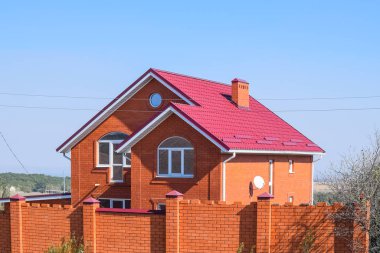 Kırmızı çatılı ve kırmızı tuğlalı bir ev. Kırmızı tuğlalı çit. Benim çatım.