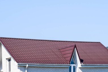 Plastik pencere ve oluklu levha kahverengi bir çatı ile ev