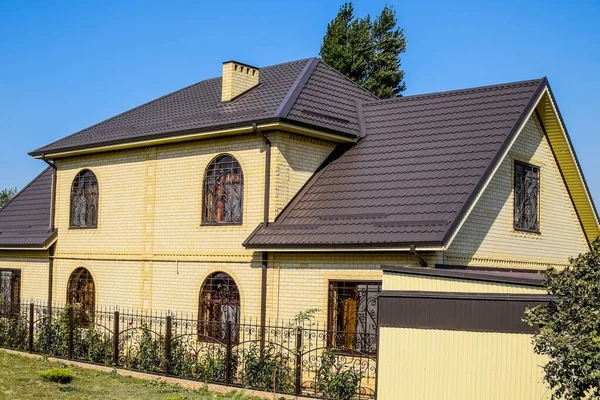 Sarı tuğlalı ve metalden yapılmış kahverengi çatılı bir ev. Ben... — Stok fotoğraf