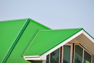 Oluklu plastik pencere ve yeşil bir çatı ile ev sh