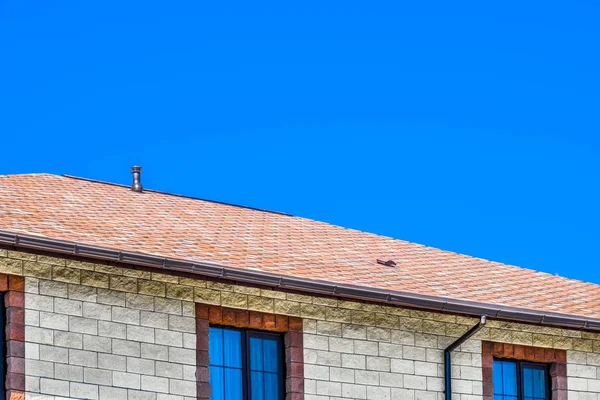 Ev bej tuğlalardan yapılmış, çatı bitu ile kaplı. — Stok fotoğraf