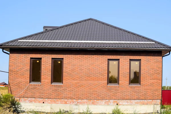 La maison avec des fenêtres en plastique et un toit en tôle ondulée. B — Photo