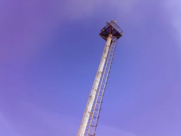 Mastro de iluminação em um fundo céu azul. Mastro com pára-raios e plataforma de observação . — Fotografia de Stock