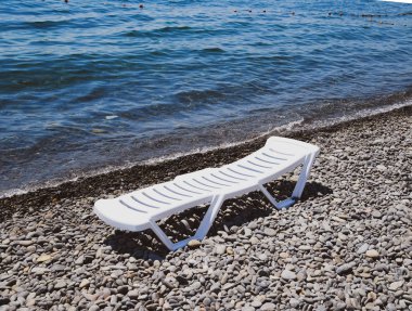 Kıyı şeridi tarafından taşlı bir plajda şezlong beyazdır. Denizin kenarında şezlong