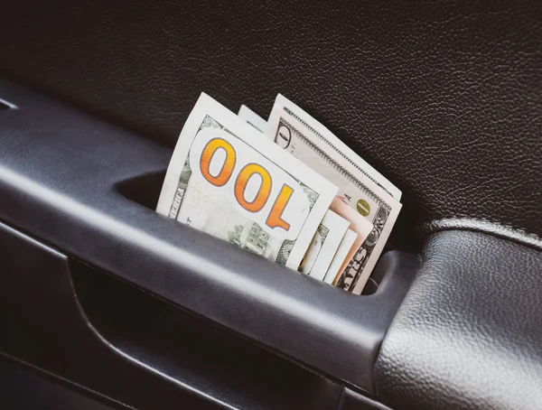 Mehrere Scheine von uns Dollar und sind in der Hälfte im Türgriff des Autos gefaltet. das Geld im Auto — Stockfoto