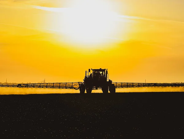 Tractor con la ayuda de un pulverizador rocía fertilizantes líquidos sobre el trigo joven en el campo. — Foto de Stock