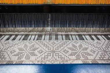 Tekstil kumaşları dokuma tezgahı bir tekstil fabrikasında iplik dokuyor. Kısa odak.