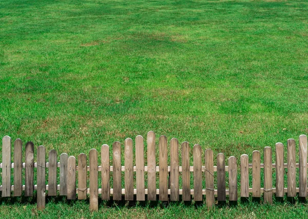 Liten trä staket i grönt gräs fält — Stockfoto