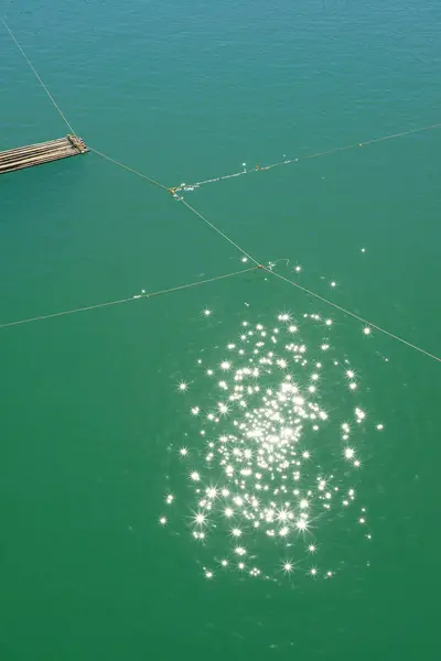 Отражение солнечных лучей в зеленом озере с веревками — стоковое фото